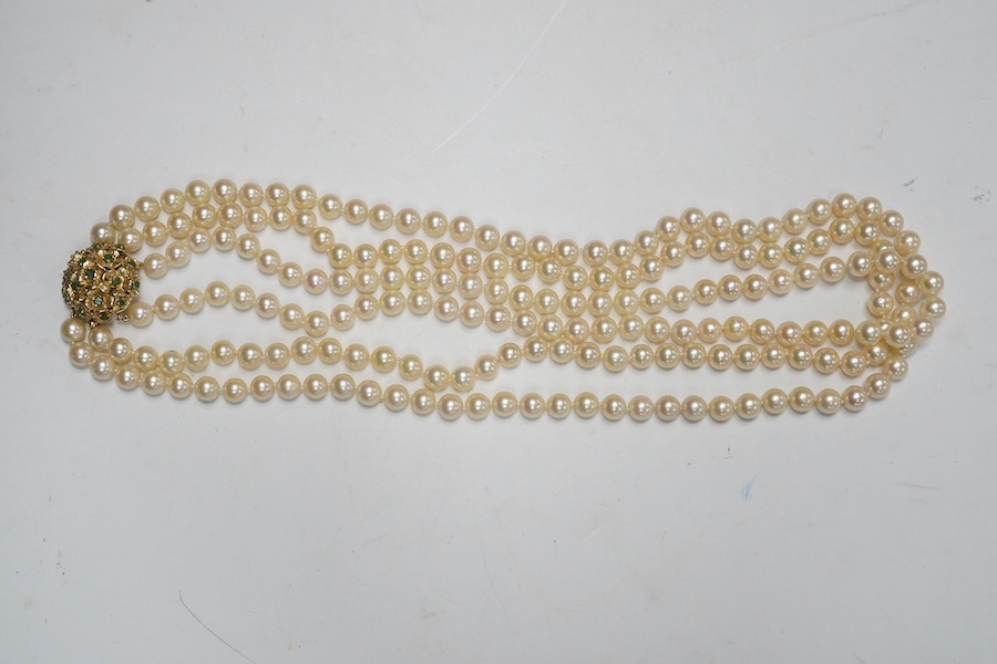 A modern triple strand culture pearl necklace, with emerald cluster set 14k clasp, 48cm. Condition - poor to fair